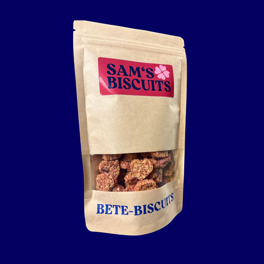 Tüte Bete-Biscuits. Schräg fotografierte hundekekse mit Gemüse und Roter Bete  in Herzform von SAM'S BISCUITS in einer Verpackung auf blauem Hintergrund
