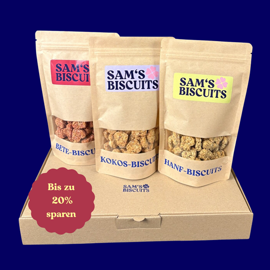 drei Tüten besonderer Hundeleckerlis von SAM'S BISCUITS auf einem Karton, ein roter Sticker signalisiert 20% sparen
